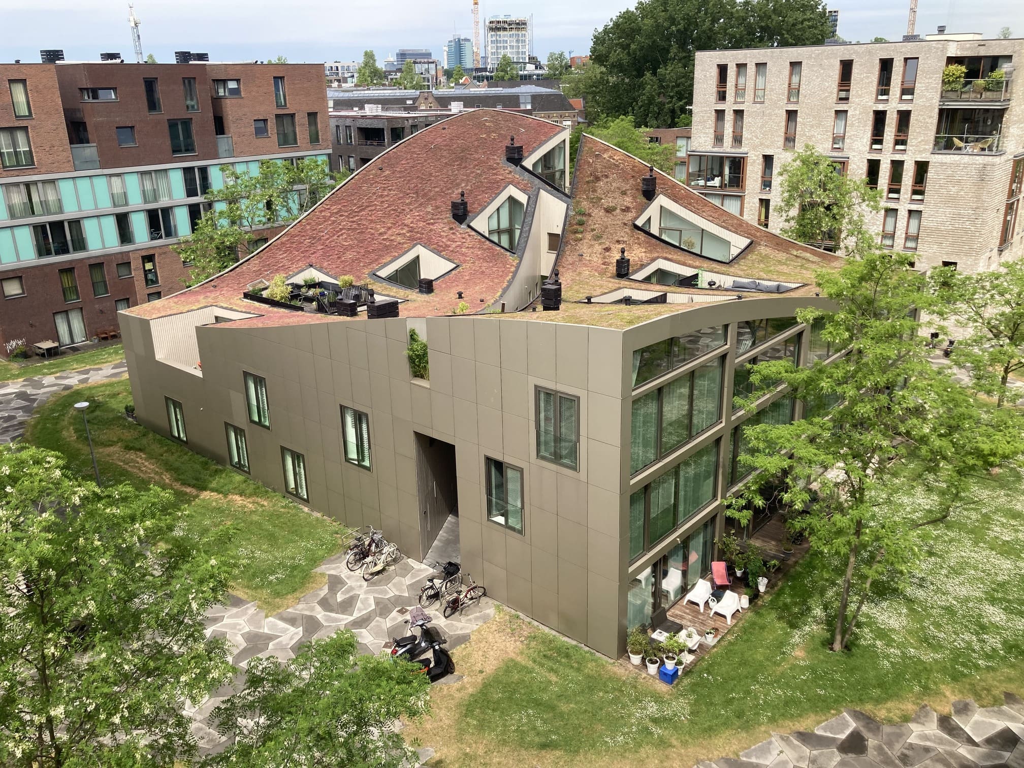 Elevated view of Blok K / Verdana showing the folded roof, roof gardens, terraces, and surrounding Funenpark buildings.