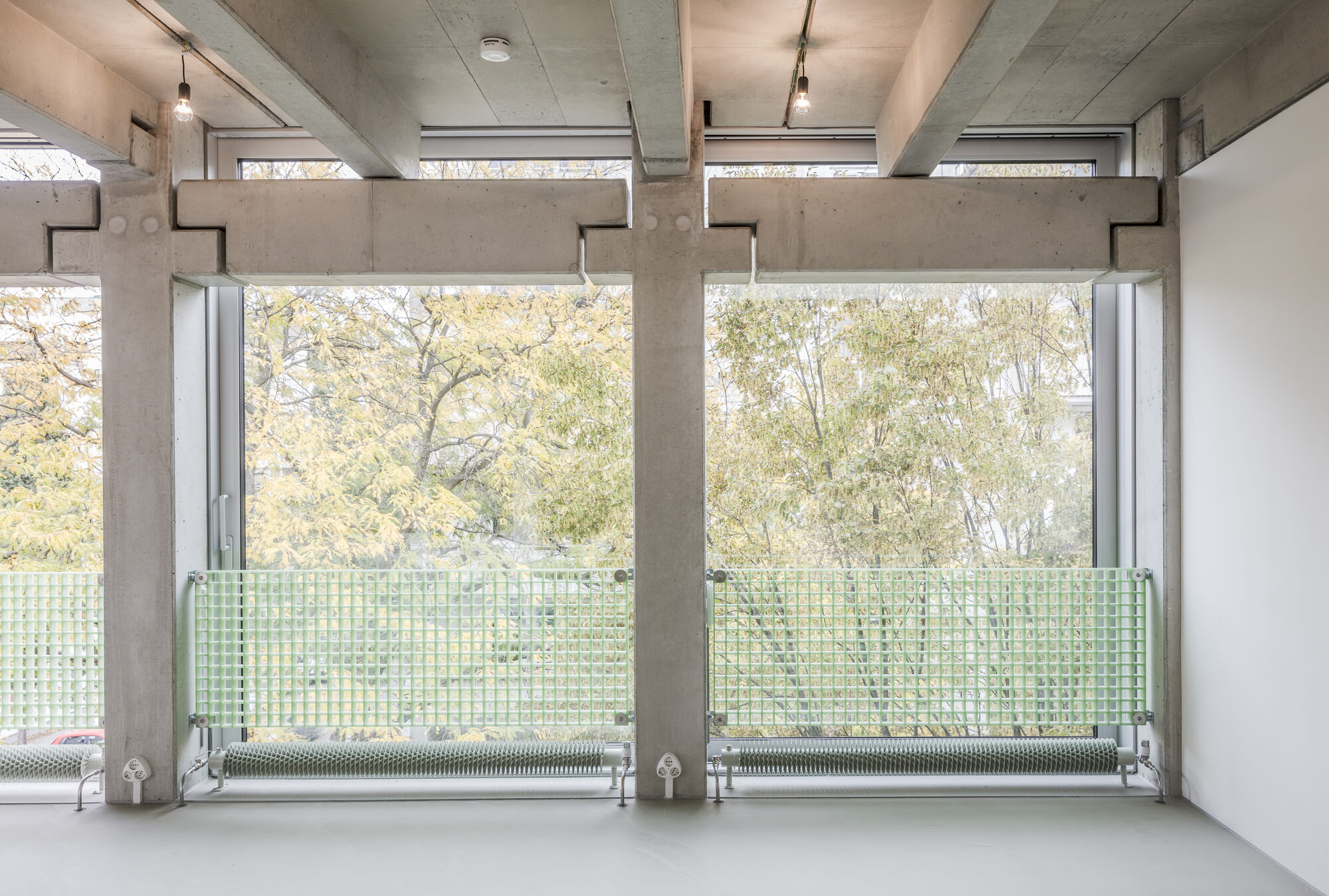 Empty Wohnregal live-work interior with exposed concrete structure, sliding glass facade, and balcony access